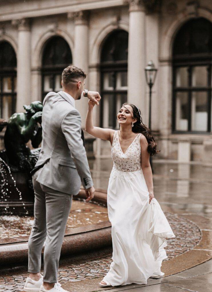 Tanzend im Regen schaut sich das Bruatpaar lachen in die Augen. Hochzeitsfotograf Hamburg. Hochzeitsfilm Hamburg