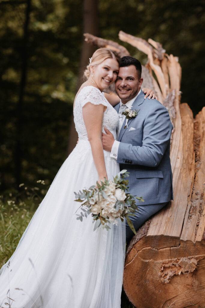 Das Brautpaar steht auf einem Baumstamm und schaut dabei in die Kamera. Hochzeitsfotograf-Hamburg