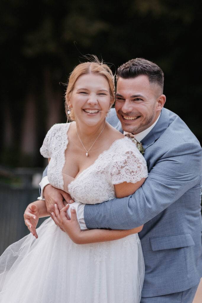 Die Braut hat Ihren Bräutigam von hinten in den Arm genommen. Hochzeitsfotograf-Hamburg