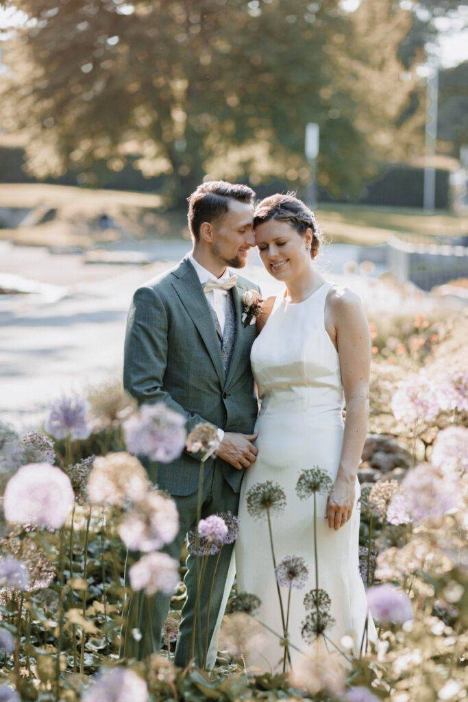 Das Brautpaar steht in einer Blumenwiese und hat sich in den Arm. Beide haben die Augen dabei verschlossen. Hochzeitsfotograf-Hamburg