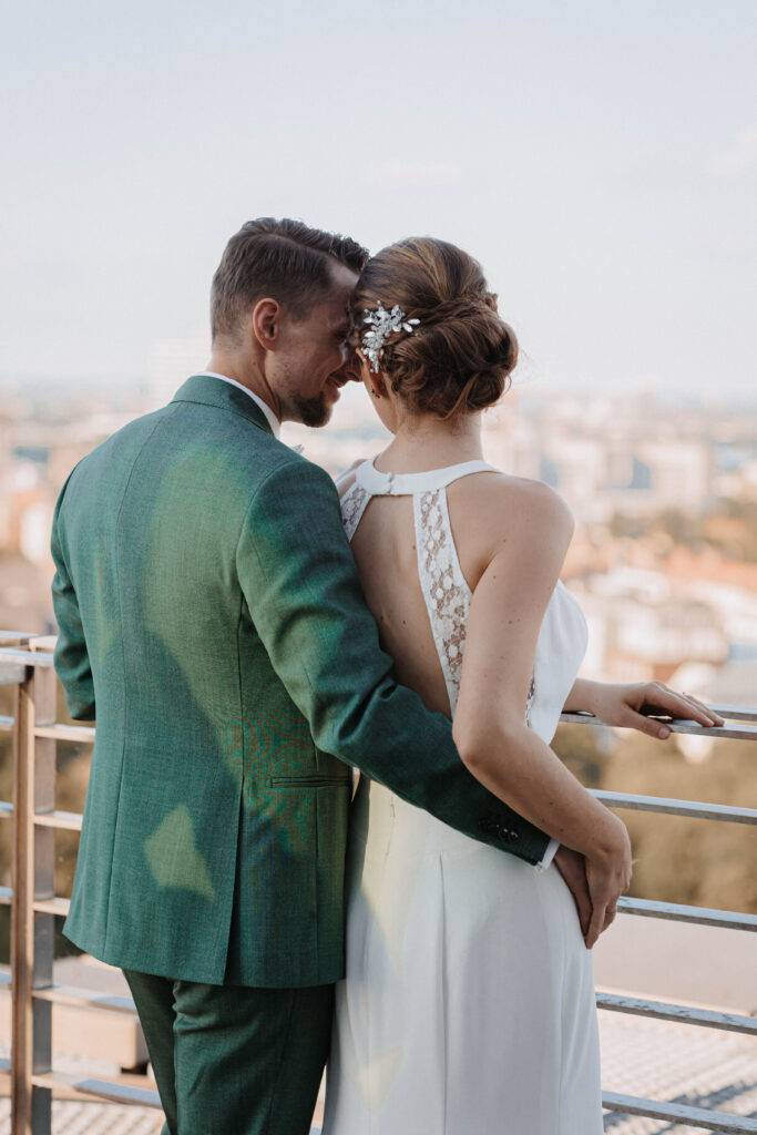 Das Brautpaar ist von hinten zu sehen. Er in einem grünen Anzug und hat seine Frau im Arm. Beide haben die Köpfe aneinander. Hochzeitsfotograf-Hamburg