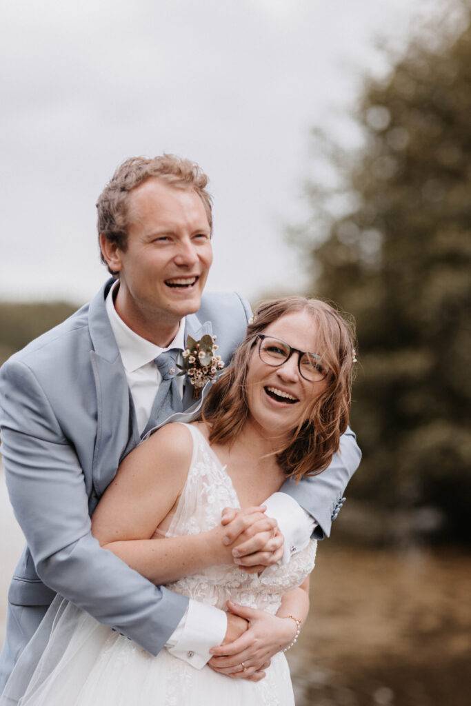 Die Braut hat Ihren Bräutigam von hinten in den Arm genommen. Hochzeitsfotograf-Hamburg