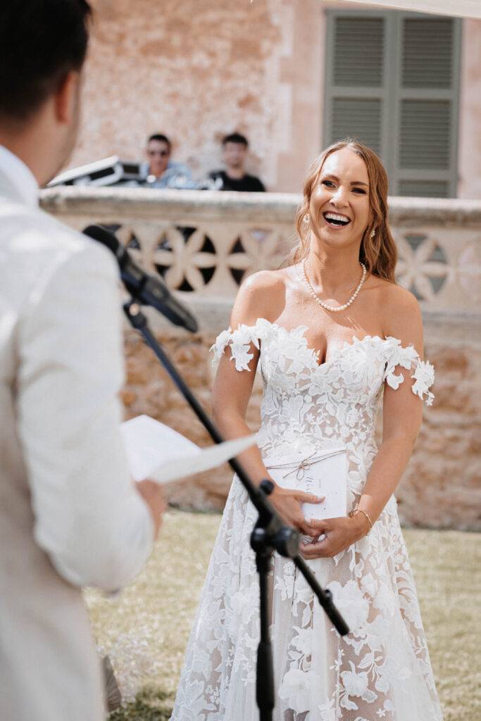 Die Braut steht bei der Trauung und schaut Ihren Bräutigam an, wie er durch das Mikrofon sein gelübde spricht