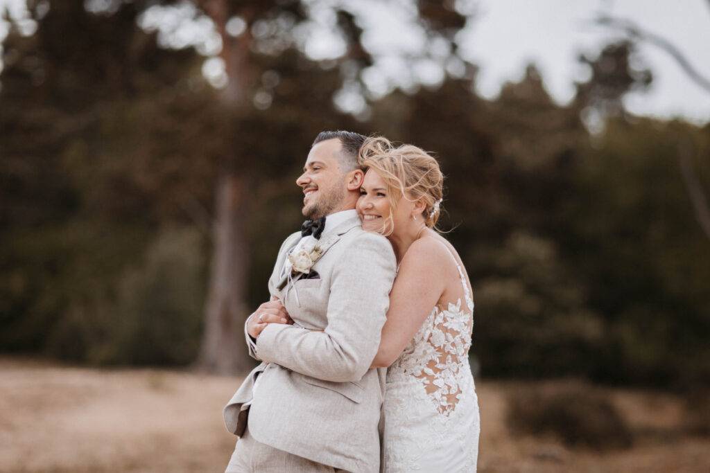 Die Braut hat Ihren Bräutigam von hinten in den Arm genommen. Hochzeitsfotograf-Hamburg