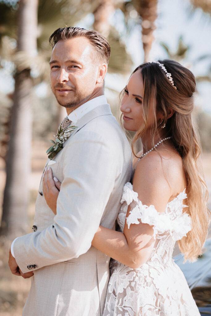 Das Brautpaar steht hintereinander auf Mallorca unter eine Palme. Hochzeitsfotograf-Hamburg