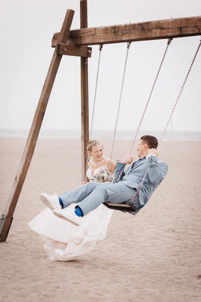 Das Brautpaar sitzt auf einer Schaukel und beide Schaukeln und gucken sich dabei an
