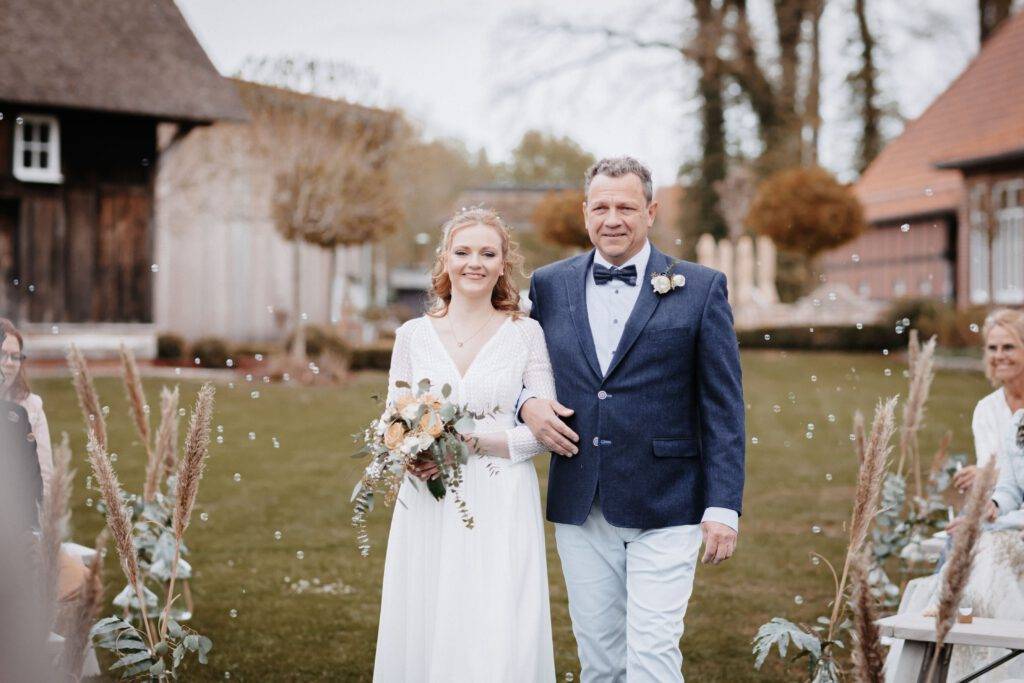 Die Braut schaut mit ihrem Vater zusammen in die Kamera. Hochzeitsfotograf-Hamburg