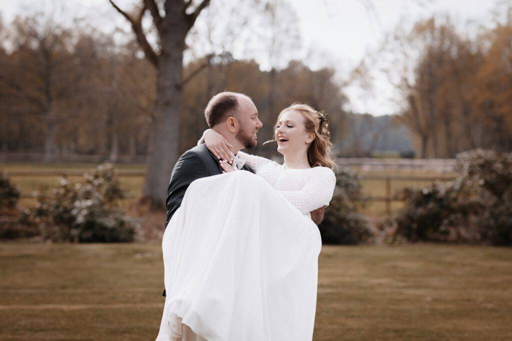 Der Bröutigam hat die braut auf dem Arm und beide schauen sich dabei in die Augen.Hochzeitsfotograf-Hamburg