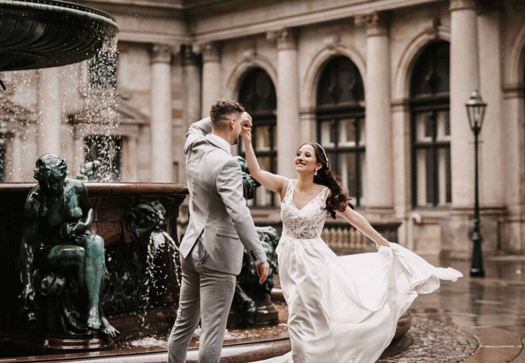 ein junges dunkelhaarige s Pärchen tanzt inmitten des Hamburger Rathauses.