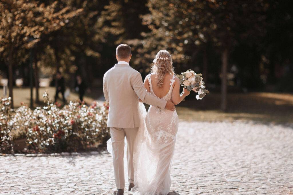 Eine Rückansicht vom einem Brautpaar, wie sie eine Straße entlang gehen.