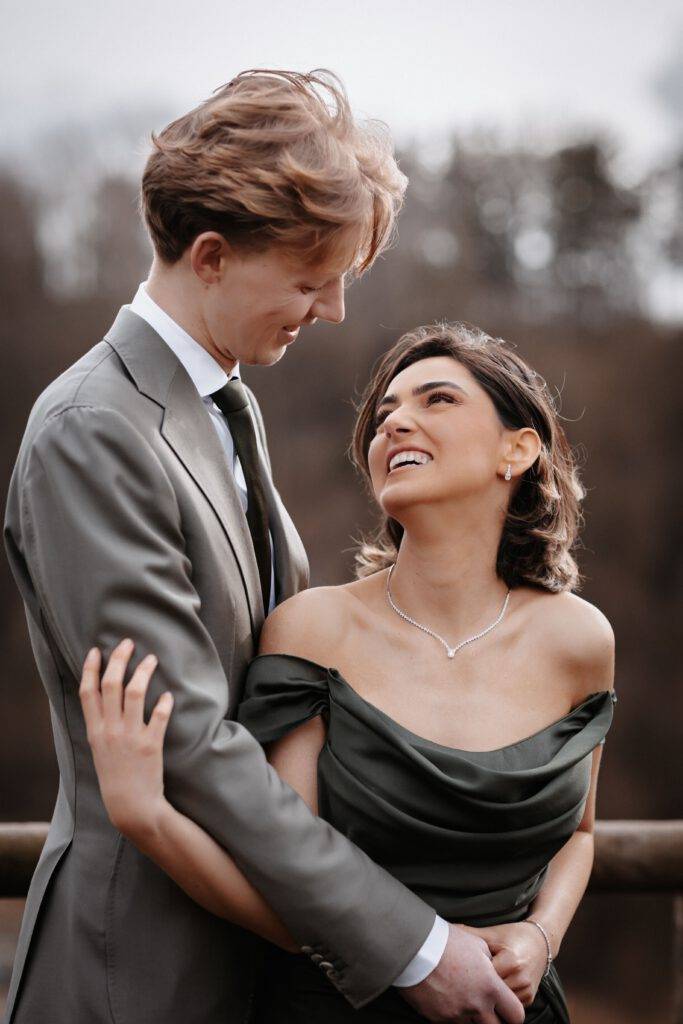 Das Brautpaar steht hintereinander und schaut sich lachend in die Augen. Hochzeitsfotograf Hamburg. Hochzeitsfilm Hamburg