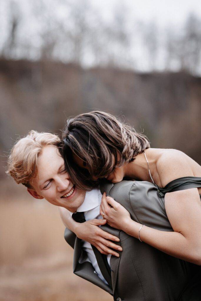 Die Braut ist auf dem Rücken des Bräutigams und lachen. Die Haare der Braut verdecken ihr gesicht. Hochzeitsfotograf Hamburg. Hochzeitsfilm Hamburg