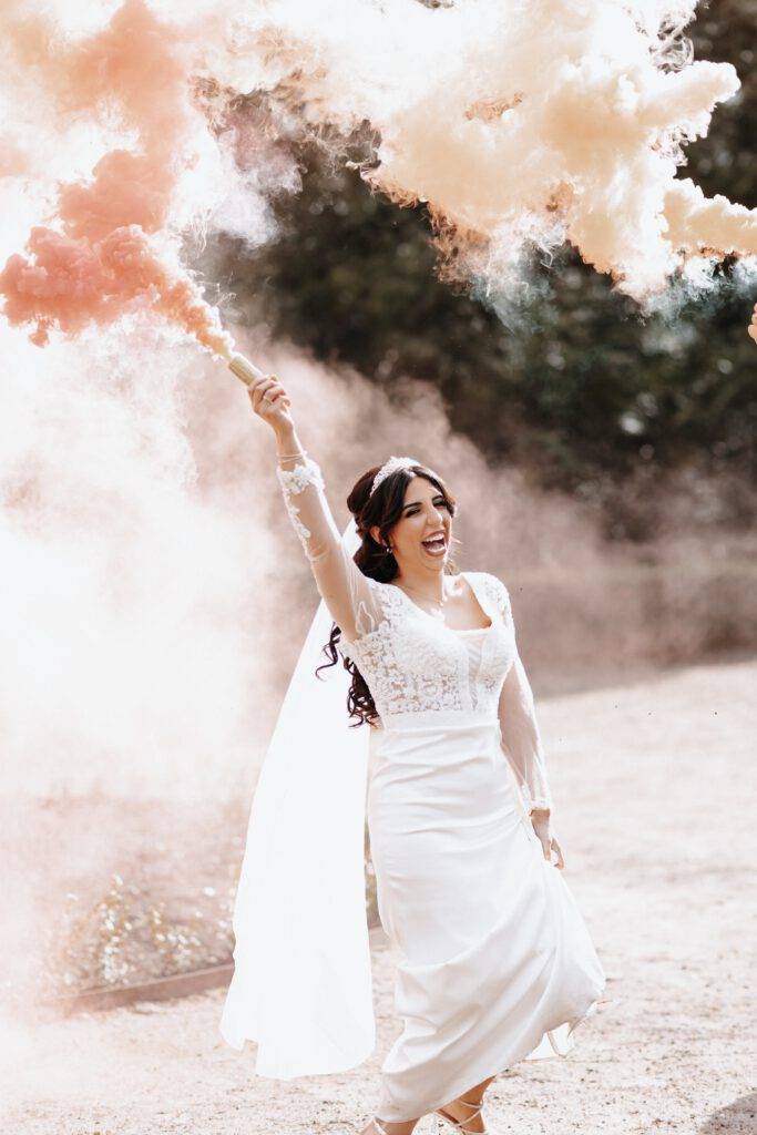 Die Braut hat eine Rauchbombe in der Hand, die sie in die Luft hält. Roter Rauch kommt dort raus. Hochzeitsfotograf Hamburg. Hochzeitsfilm Hamburg