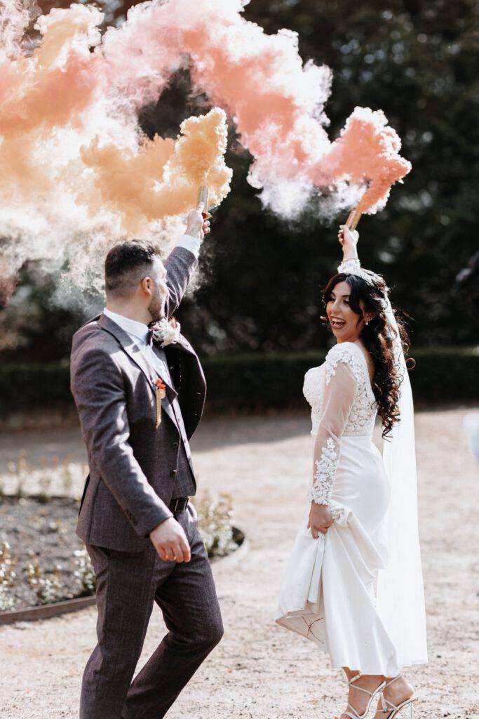 Das Brautpaar läuft im Kreis mit einer Hand nach oben, wo sie eine Rauchbombe festhalten. Hochzeitsfotograf Hamburg. Hochzeitsfilm Hamburg