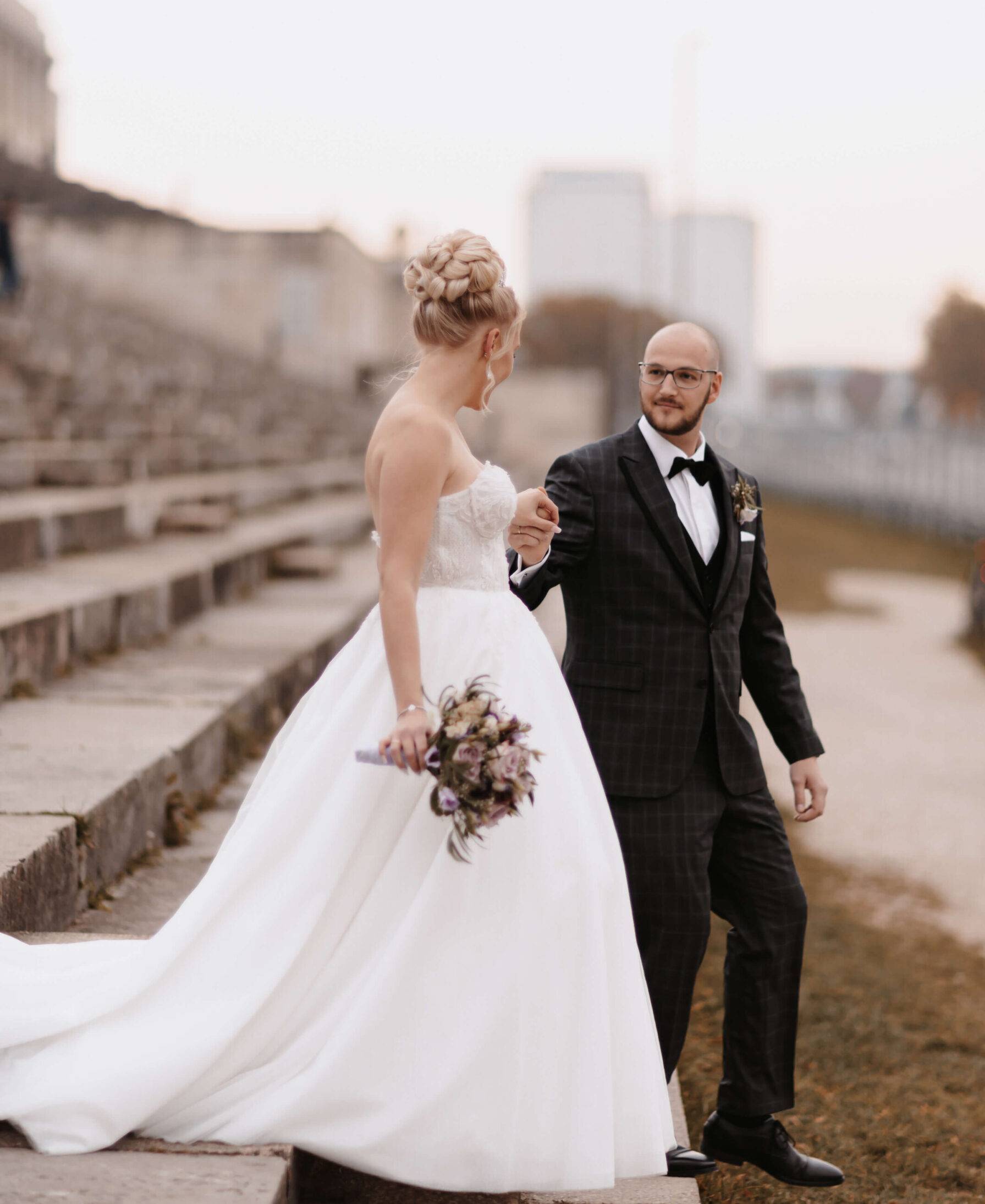 Das Brautpaar ist seitlich zu sehen. Sie schauen sich an und gehen eine Treppe runter. Dabei halten sie ihre Hand. Hochzeitsfotograf Hamburg. Hochzeitsfilm Hamburg