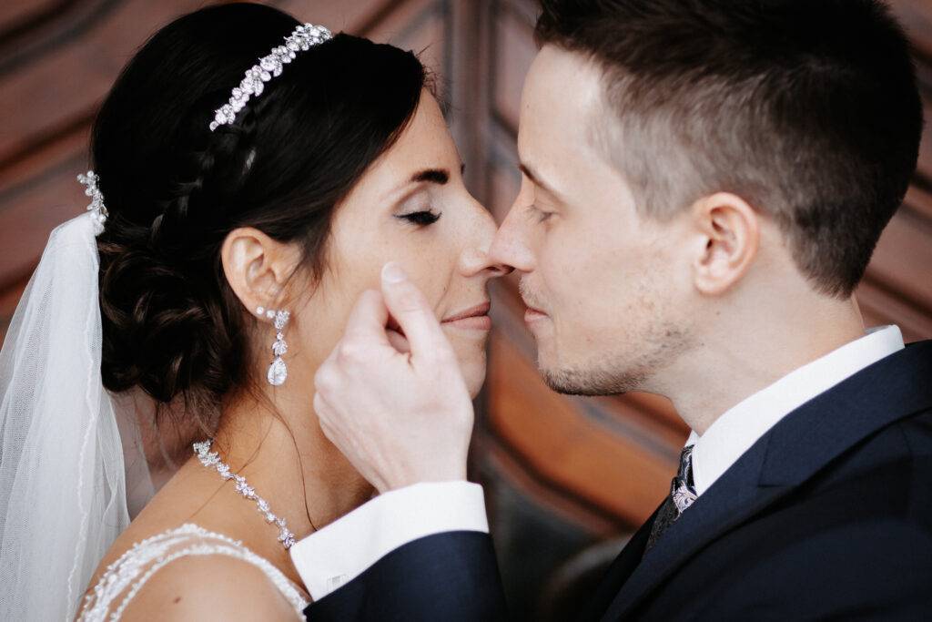 Nahaufnahme während sich Braut und Bräutigam Nase an Nase befinden. Der Bräutigam streift mit der Hand der Braut über die Wange. Hochzeitsfotograf Hamburg. Hochzeitsfilm Hamburg