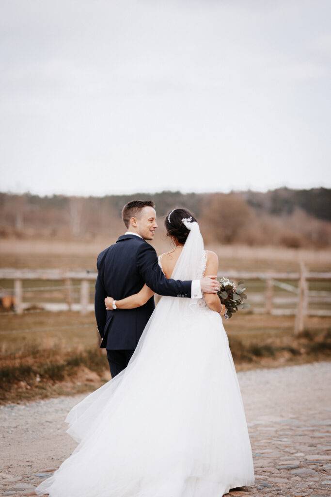 ineinandergehakt geht das Brautpaar die Straße entlang. Sie sind von hinten zu sehen. Hochzeitsfotograf Hamburg. Hochzeitsfilm Hamburg