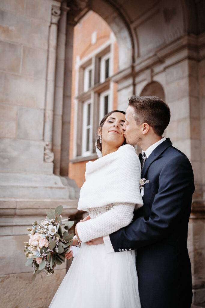 Das Brautpaar steht vor dem Rathaus Harburg und küsst sich. Hochzeitsfotograf Hamburg. Hochzeitsfilm Hamburg