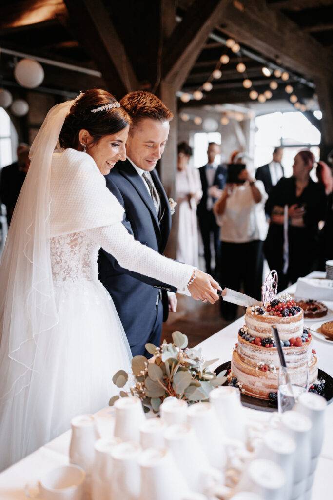 Das Brautpaar schneidet die Hochzeitstorte an. Hochzeitsfotograf Hamburg. Hochzeitsfilm Hamburg