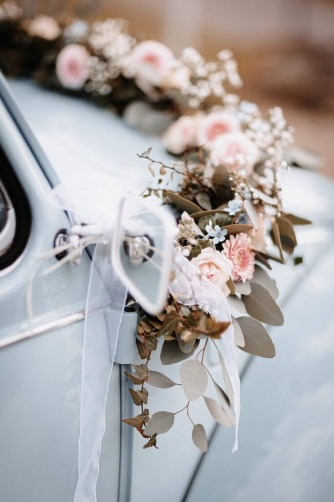 Blumendeko am Hochzeitsfahrzeut. hellblaues Auto. Braut und Bräutigam vor dem Pastor bei der Trauung. Hochzeitsfotograf Hamburg