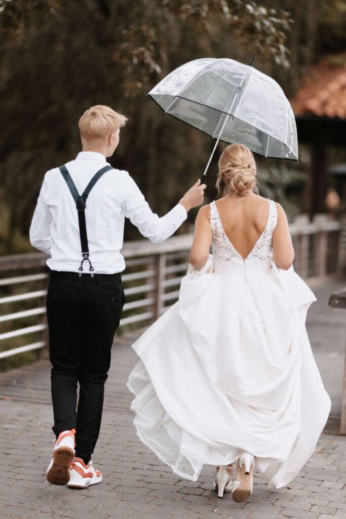 Die Braut mit Ihrem Sohn und der Sohn hält einen Regenschirm