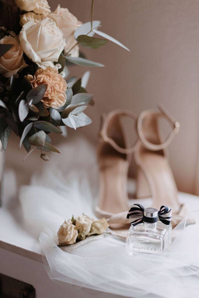 Detailaufnahme von Schuhen, Parfüm und dem Brautstrauß